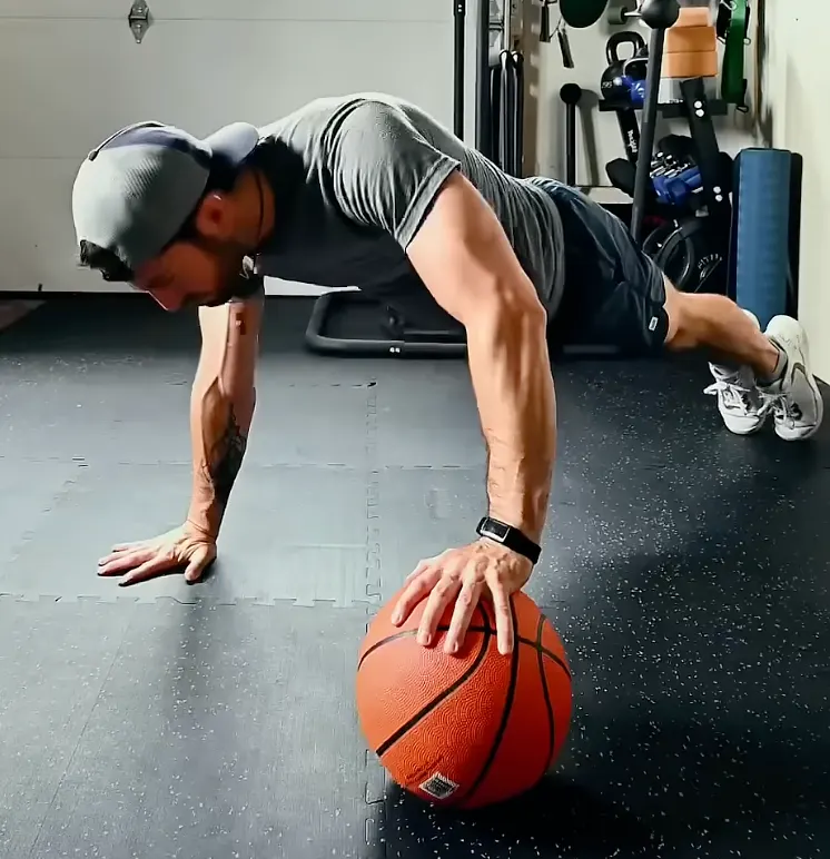 Uneven push-up with one hand on a basketball